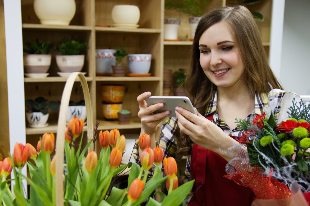 Woman taking photo of tulips in shop