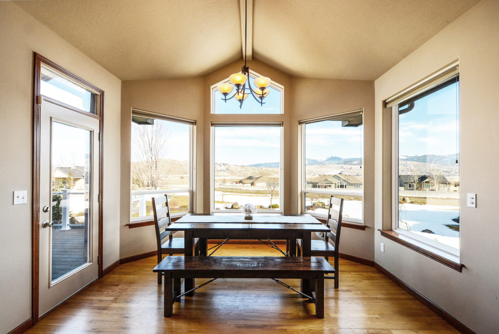 Large windows in a home’s dining room look out on a snowy yard