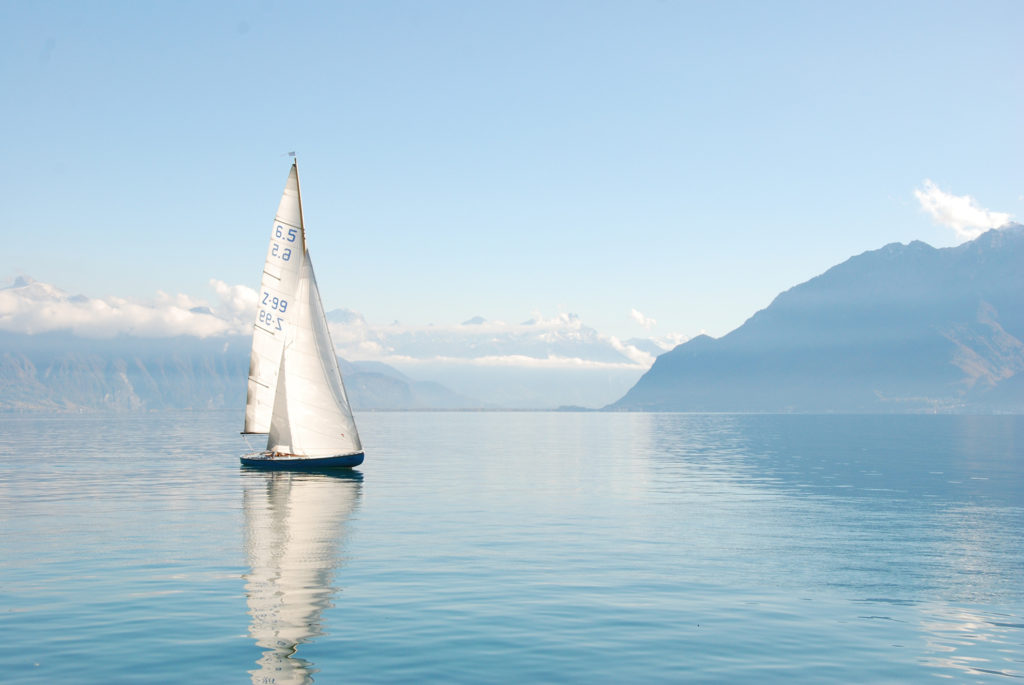 A sailboat on a sunny day with a view of the mountains.