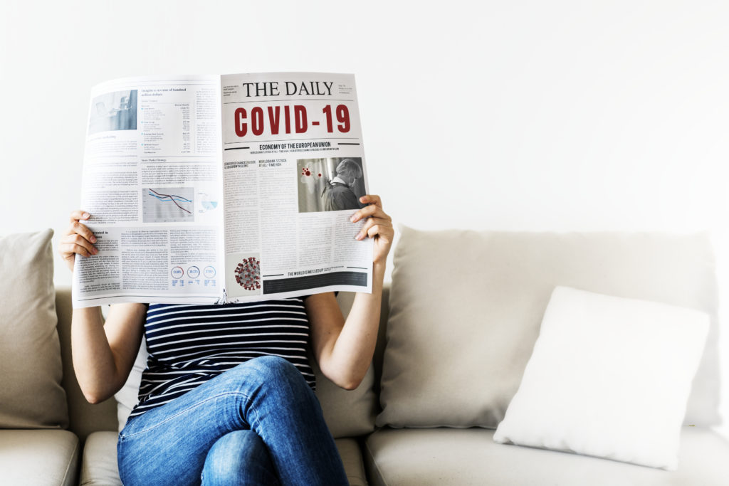 Person holding newspaper with covid-19 information