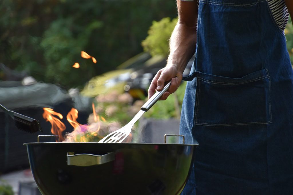 Man holding barbecue kitchen tool to move burguers at a grill